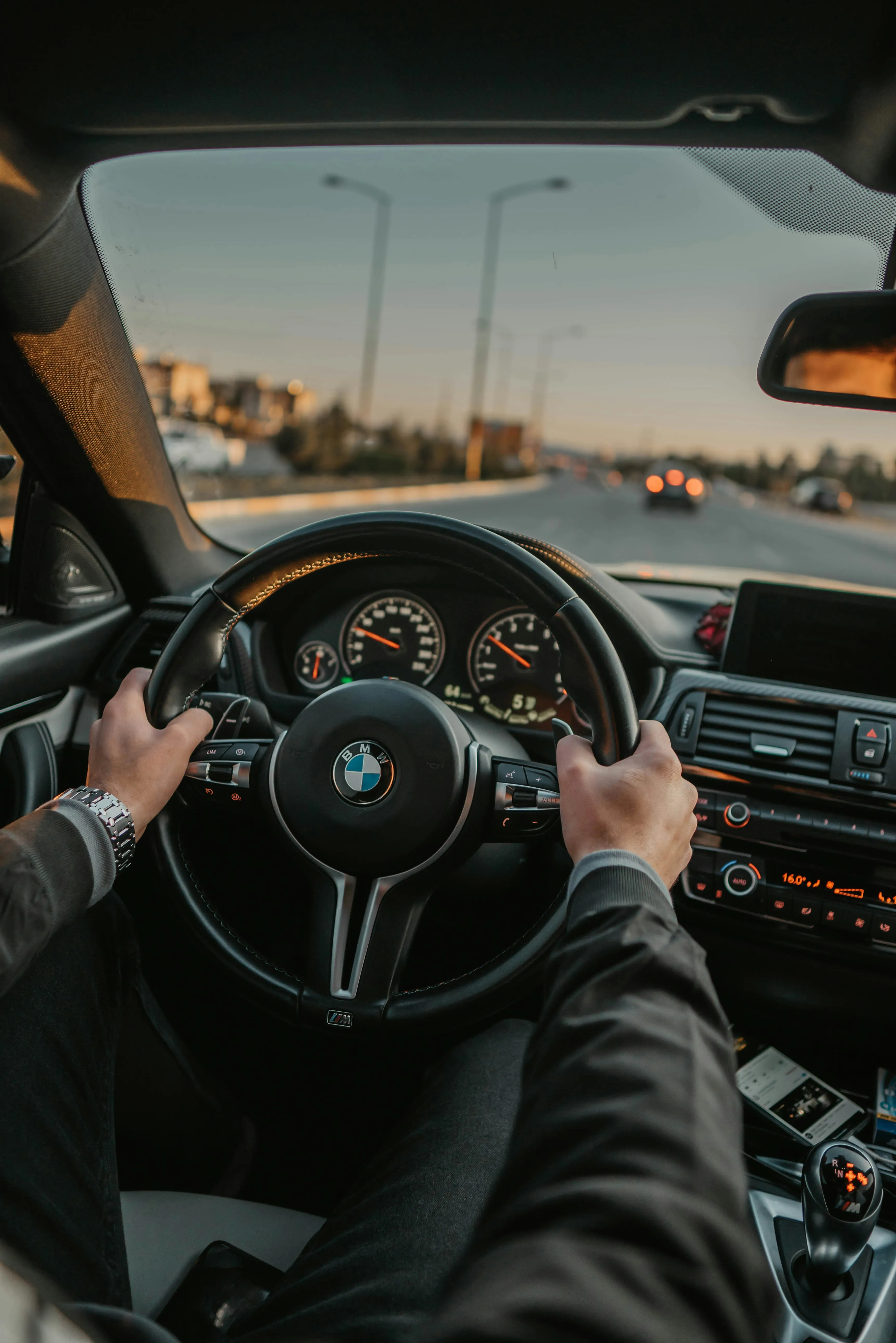 Fahrschüler am BMW-Steuer mit Blick auf die offene Straße bei Sonnenuntergang